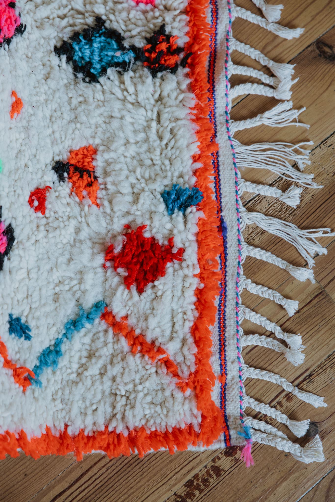 détails frange et laine douce et épaisse Détail de la bordure orange fluo d'un tapis berbère multicolore
